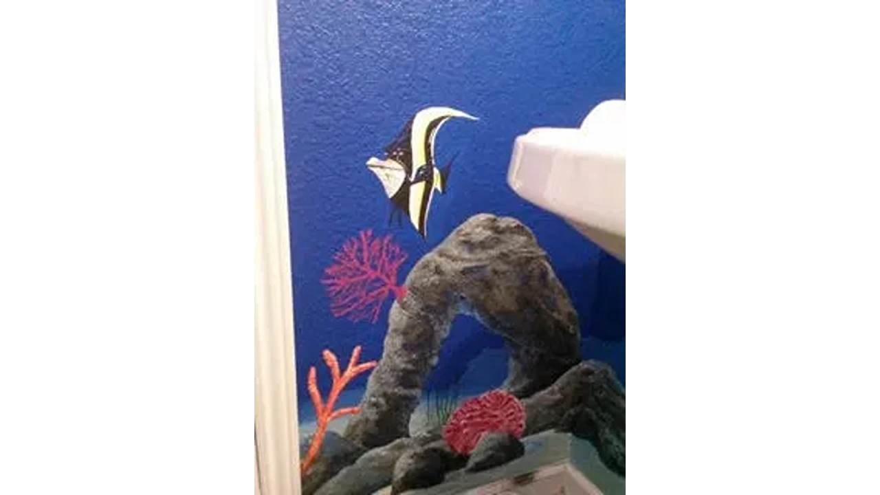 A bathroom with a fish and coral mural painted on the wall.
