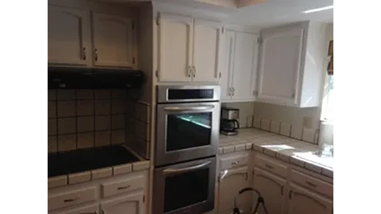 A kitchen with two ovens and white cabinets.